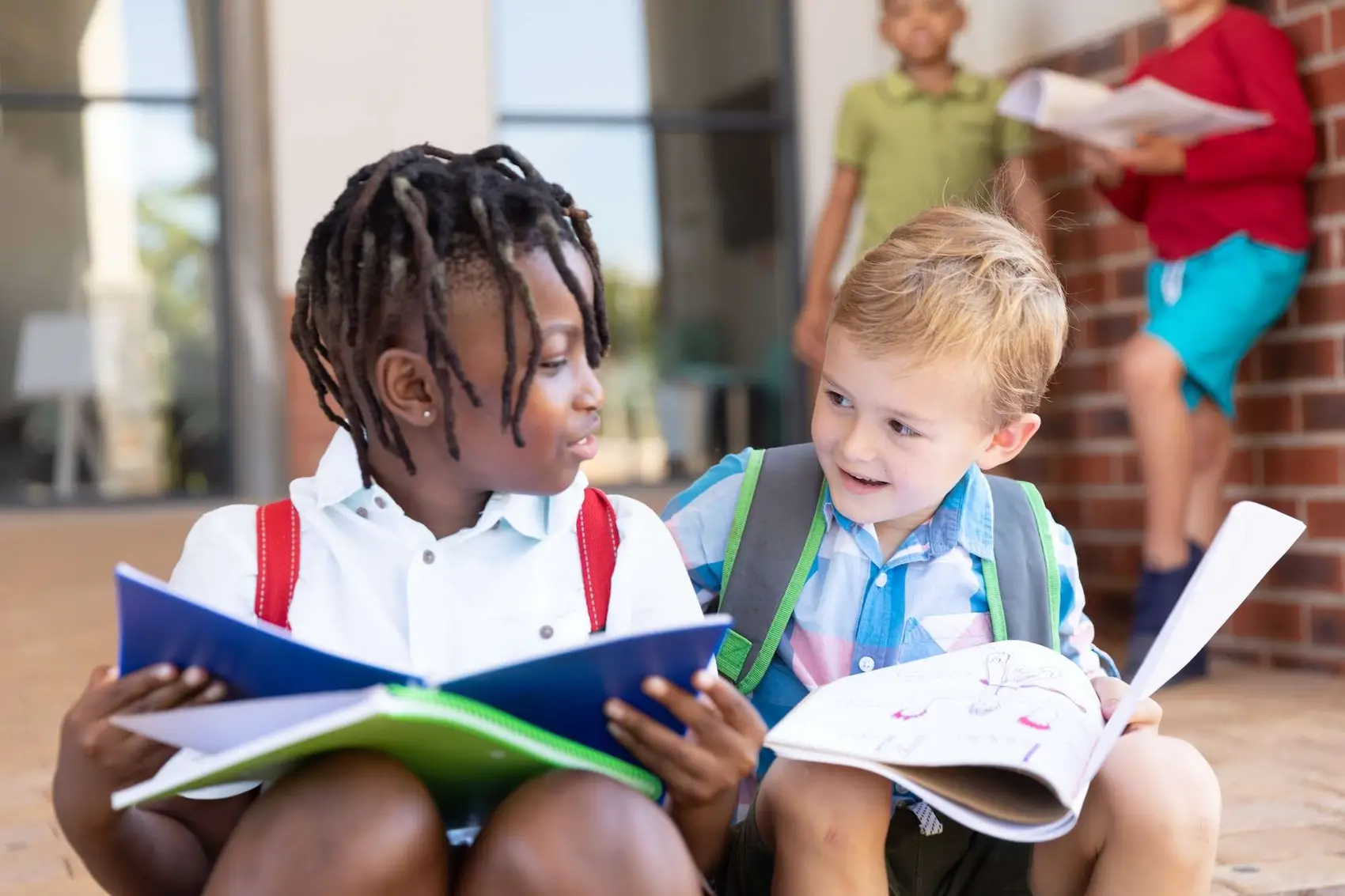 Multiracial elementary schoolboys studying while sitting on floor in school